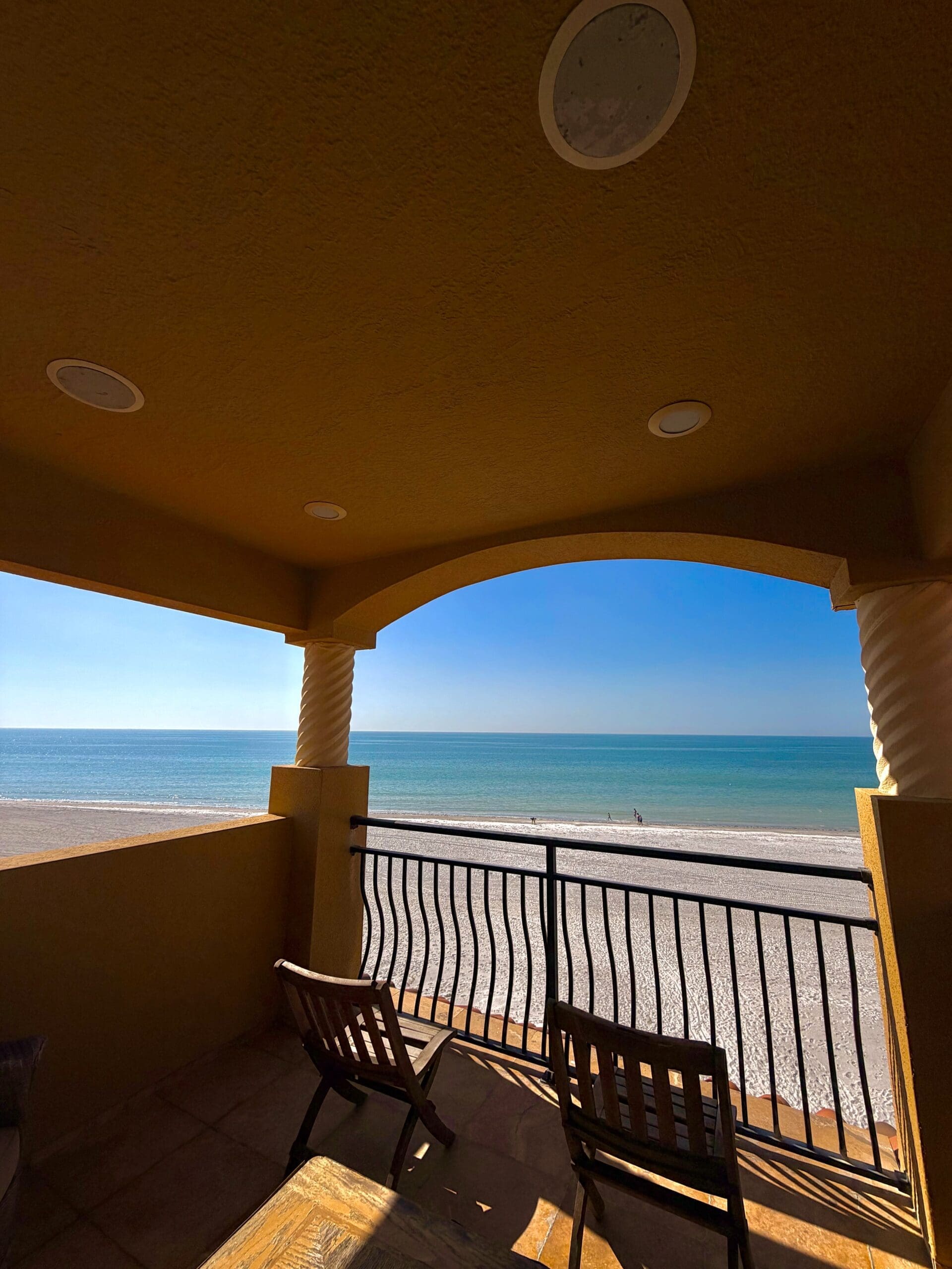 Oceanfront balcony with chairs overlooking the beach at an Indian Rocks Beach vacation home rental.