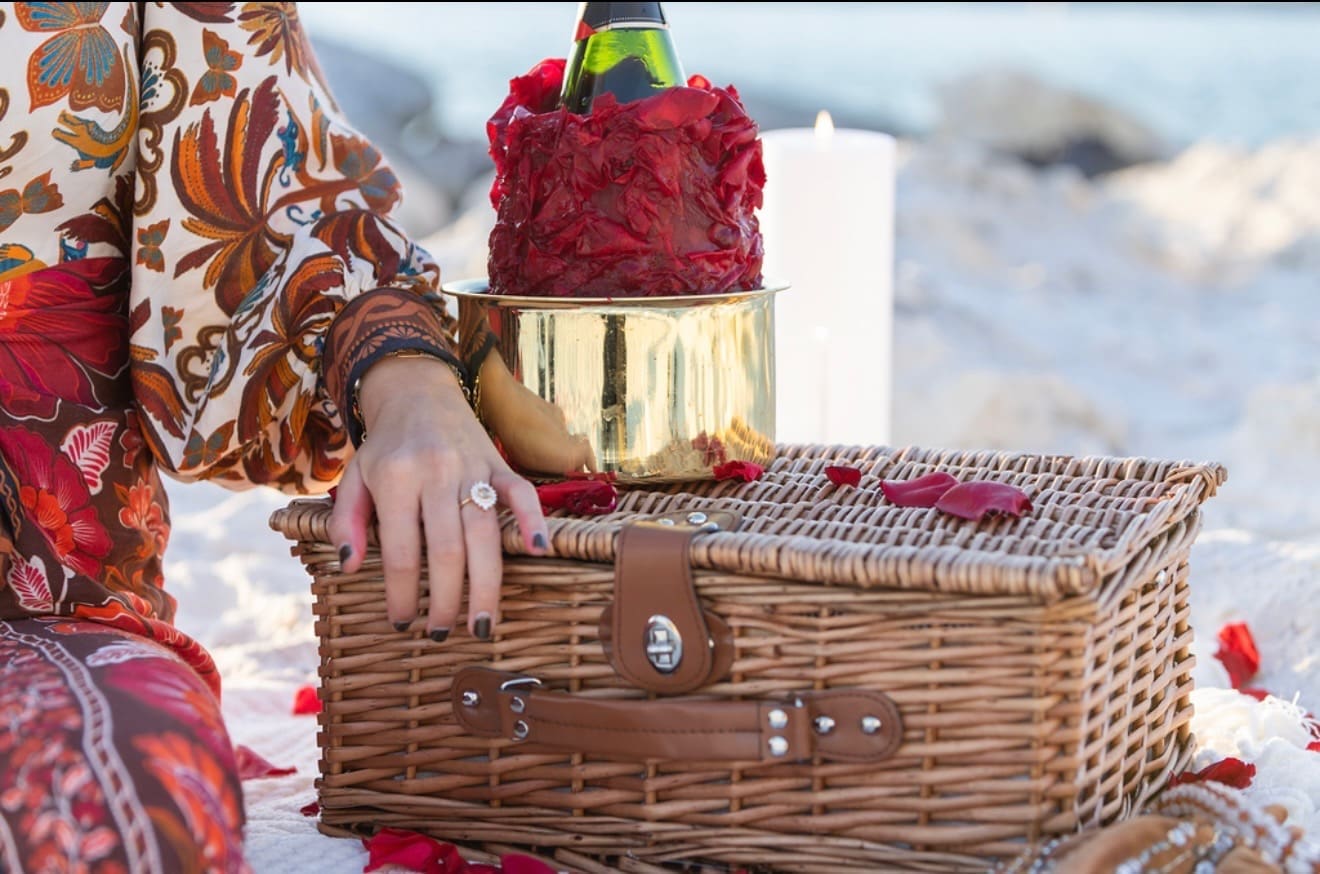 Romantic beach picnic setup with champagne, rose petals, and wicker basket at an Indian Rocks Beach vacation rental perfect for engagements.