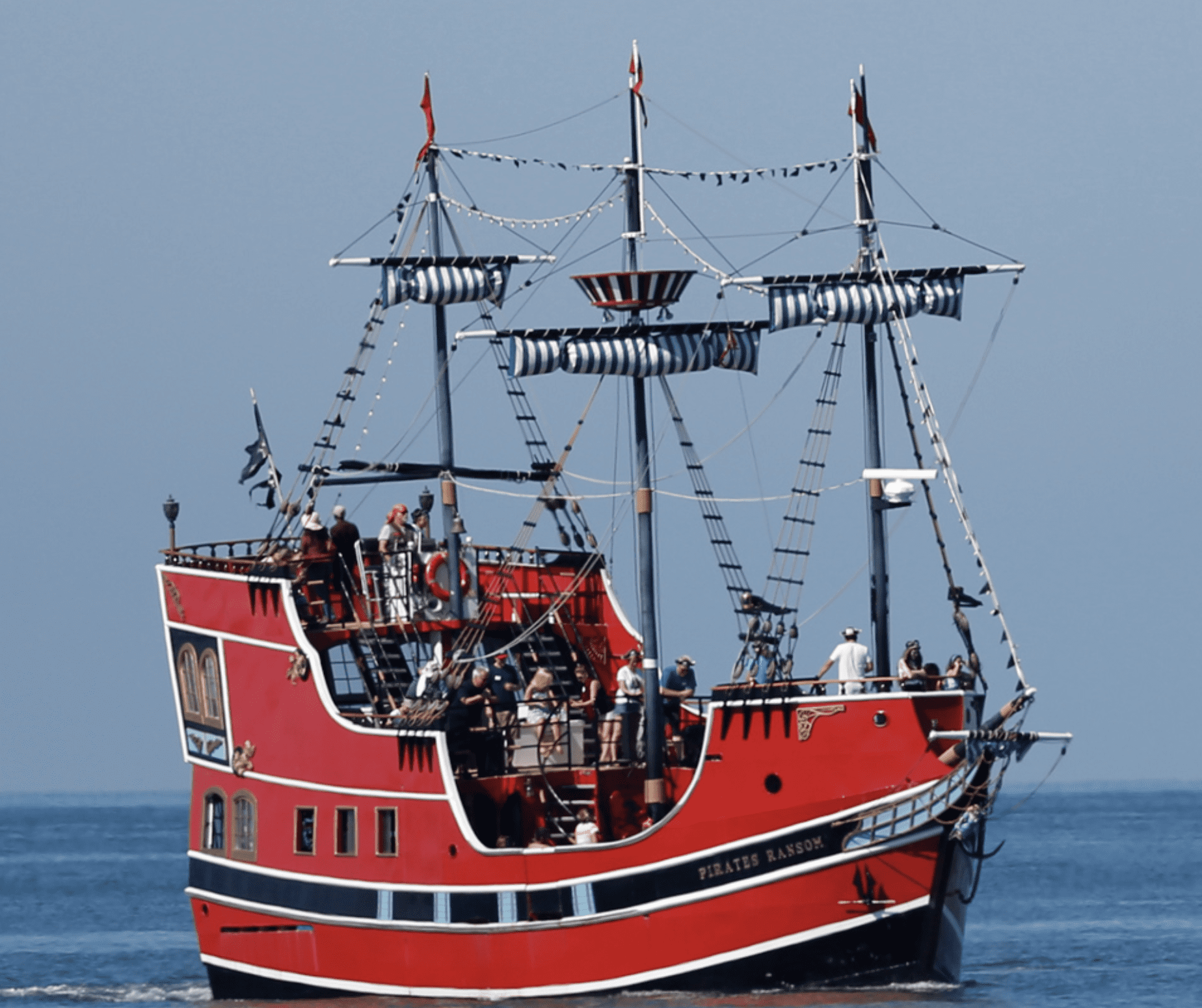 Large red pirate ship cruising on the water with passengers onboard.