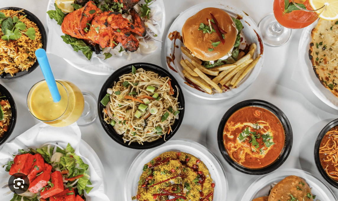 A large assortment of Indian dishes including noodles, curries, snacks, naan, and drinks.