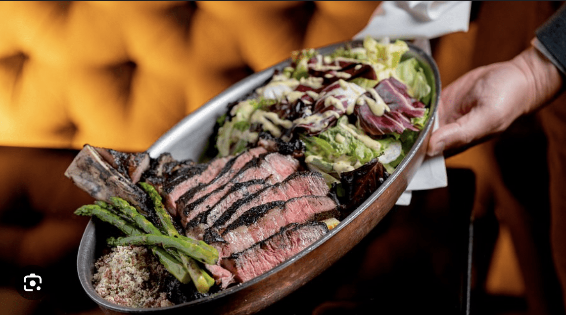 Sliced grilled steak served with asparagus, seasoned quinoa, and a mixed greens salad.