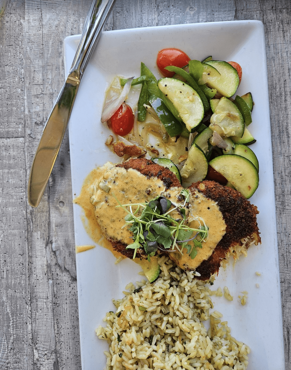 Crispy breaded fish fillets with sautéed vegetables at a Tampa Bay waterfront restaurant