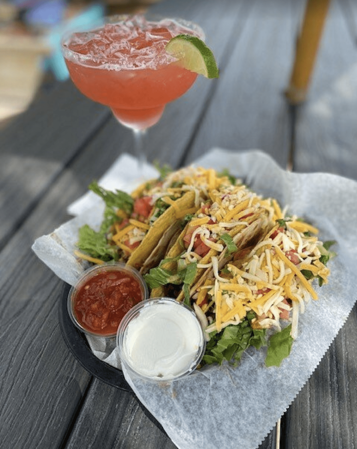 Hard-shell tacos filled with lettuce, tomatoes, shredded cheese, salsa, and sour cream.