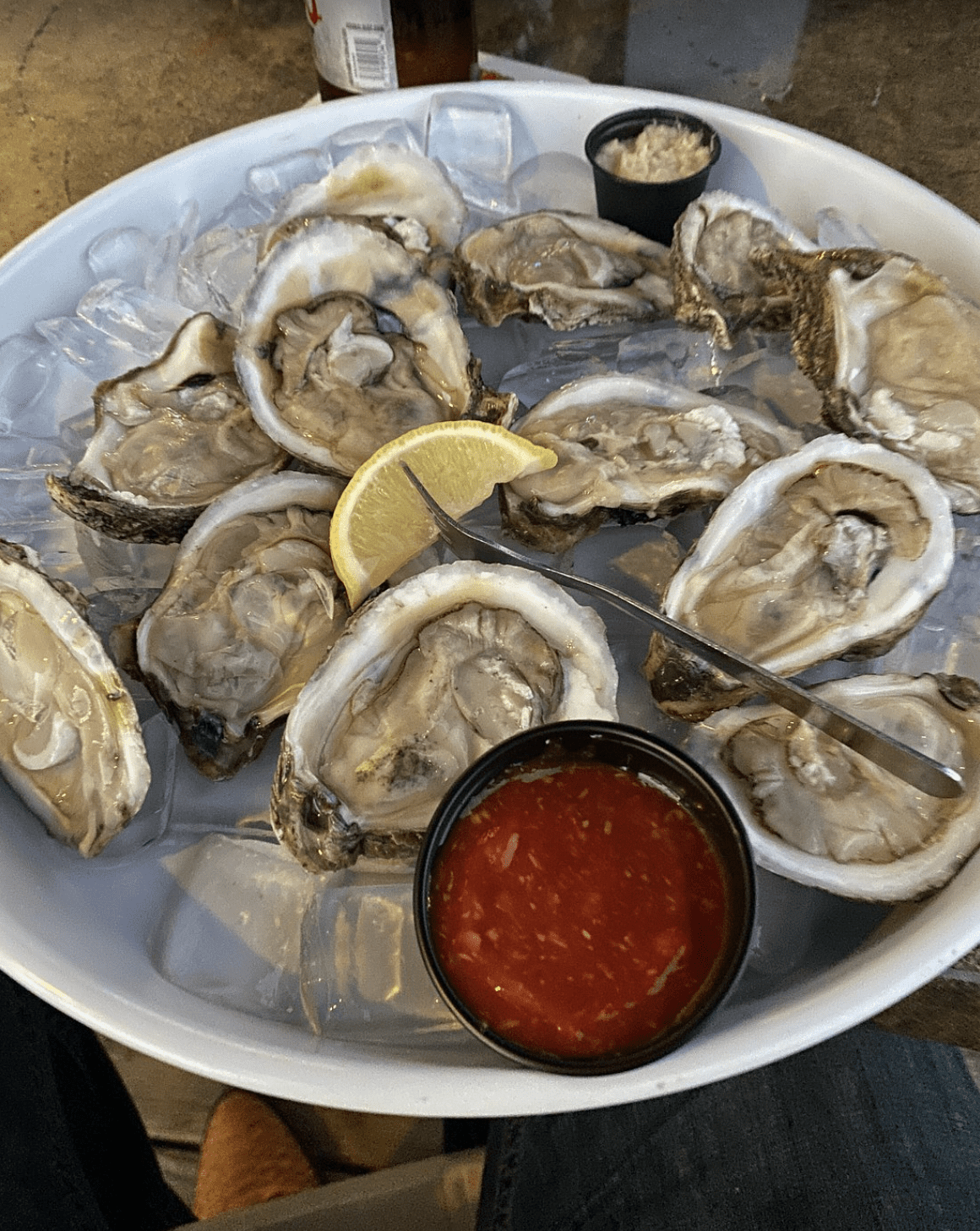 Fresh oysters on ice with a lemon wedge and cocktail sauce.