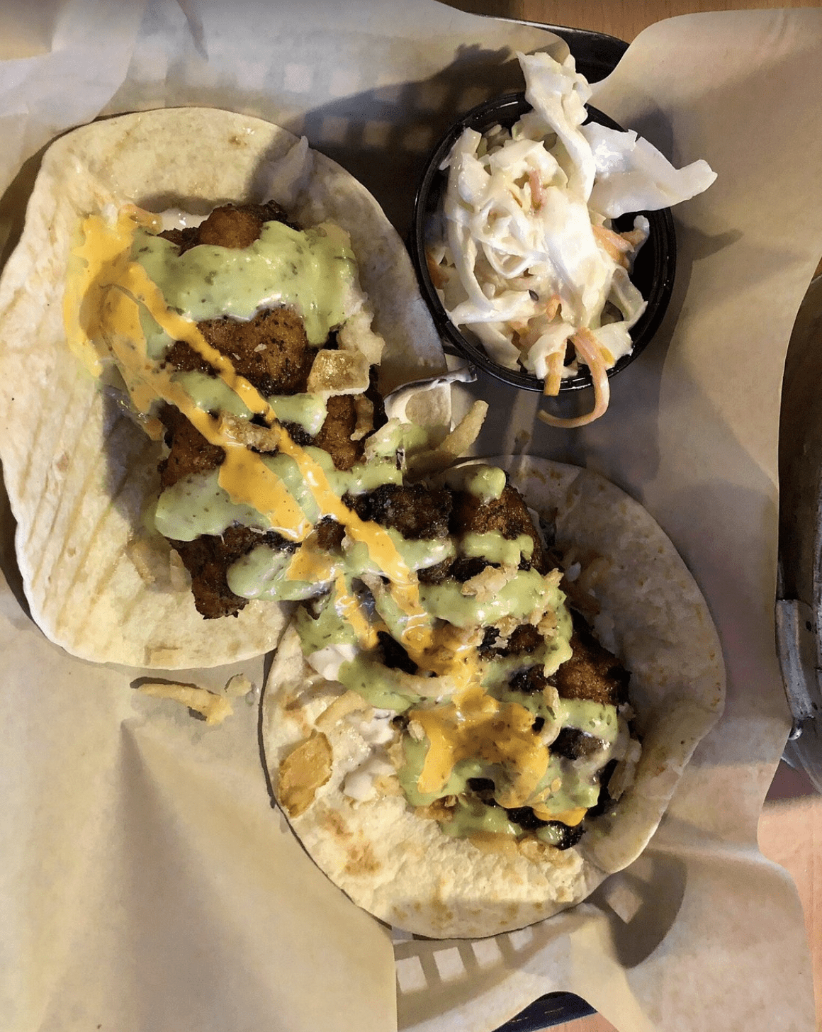 Crispy fish tacos topped with creamy sauces and served with coleslaw.