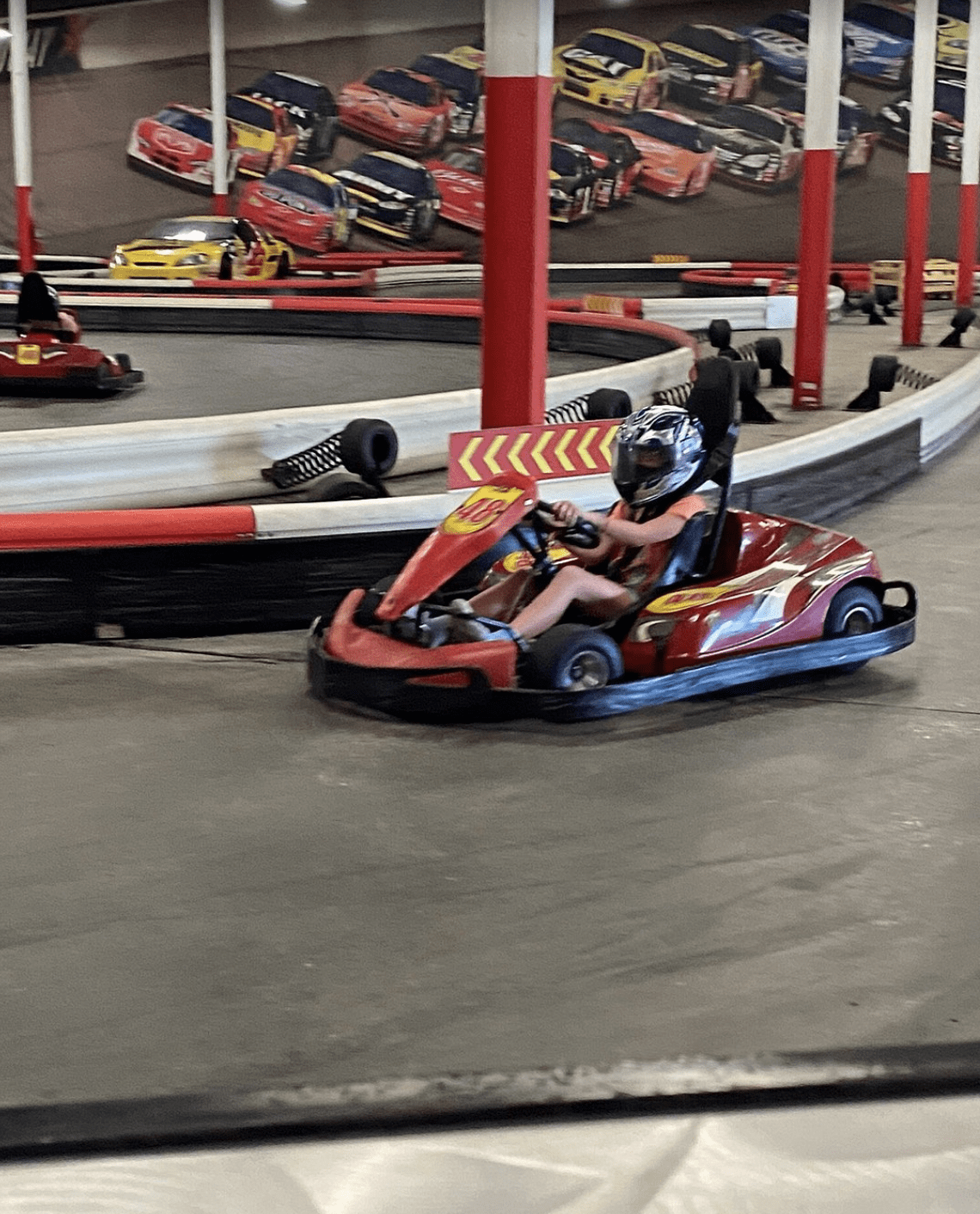 Child racing a red go-kart on an indoor track near Clearwater Beach, Florida.