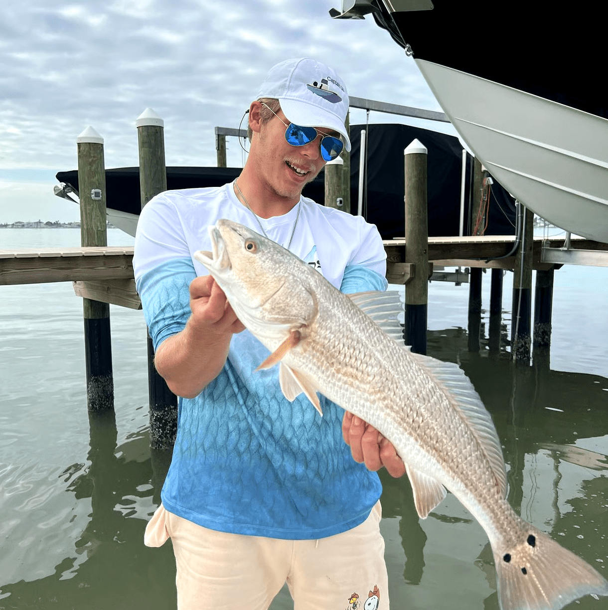Man holding a freshly caught fish during a fishing trip in Clearwater Beach, Florida.