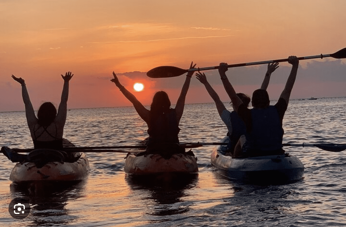 Group kayaking at sunset on the calm waters of Clearwater Beach, Florida.