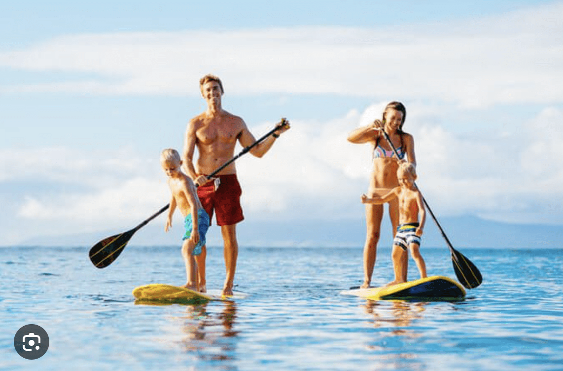 Family paddleboarding together on calm ocean water near Clearwater Beach.