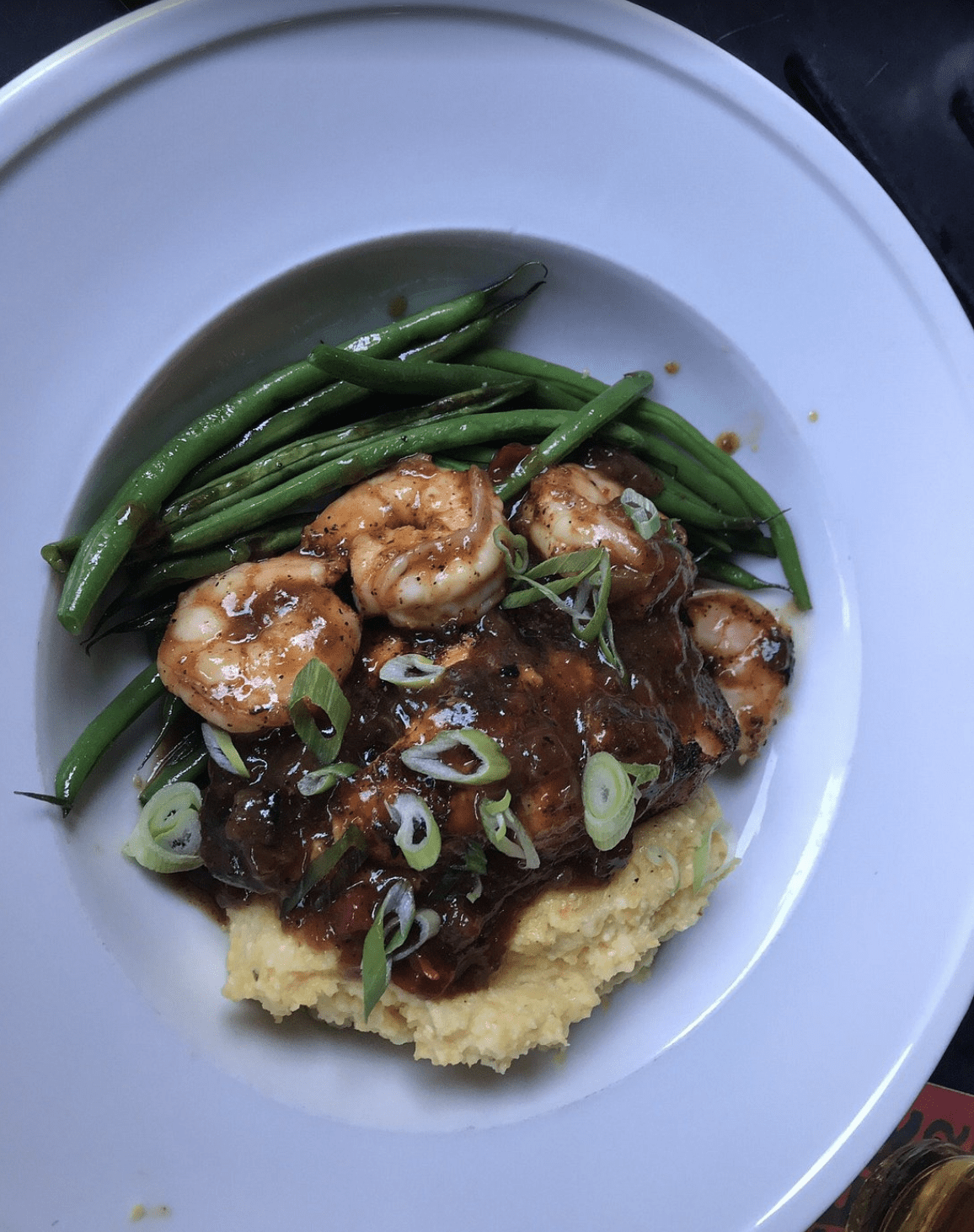 Shrimp and grits with green beans and savory sauce served at a Clearwater Beach restaurant.
