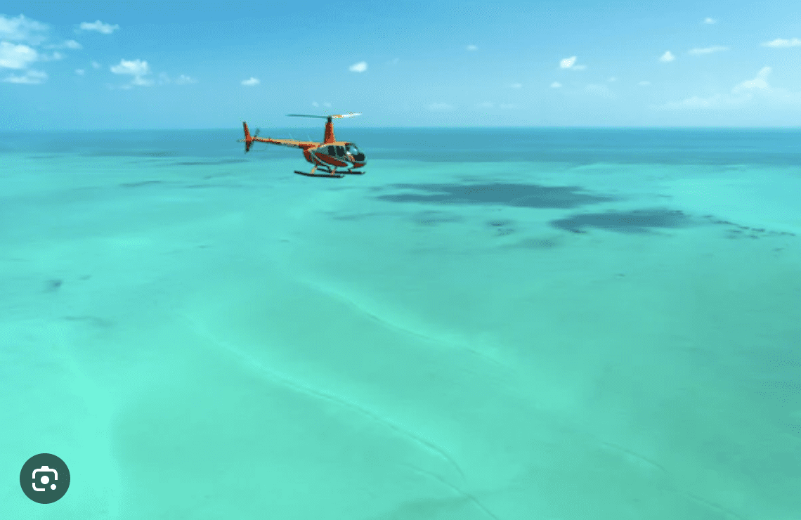 Helicopter flying over turquoise Gulf of Mexico waters near Clearwater Beach.