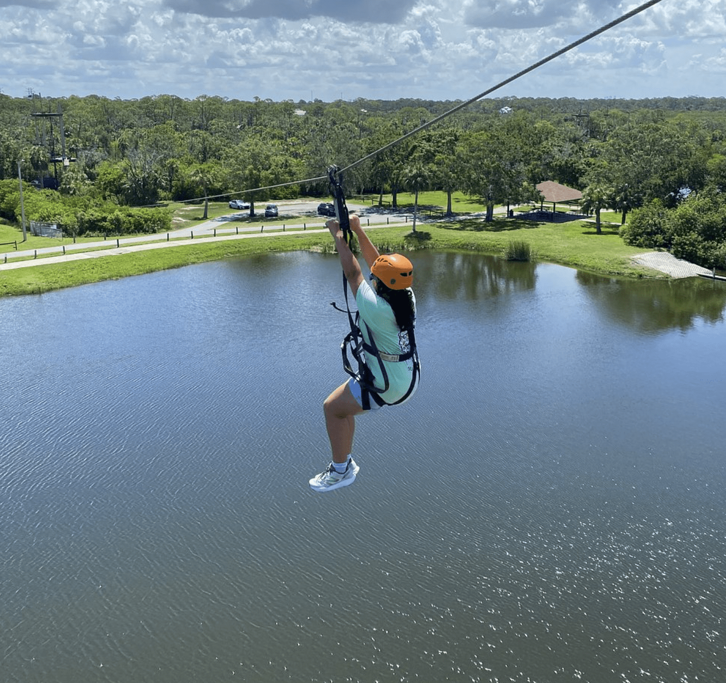 Person ziplining over a lake at Empower Adventures Tampa Bay.